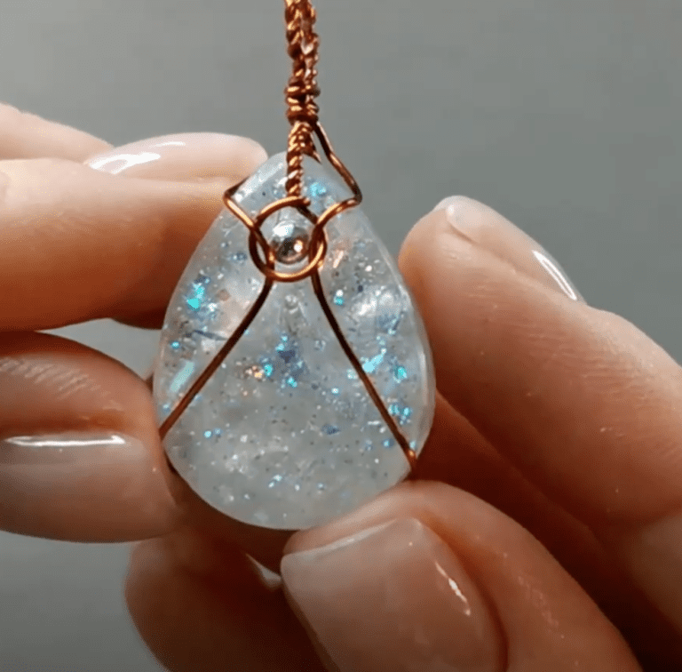 fingers holding epoxy resin opal gemstone with wirewrap